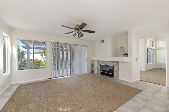 unfurnished living room featuring light tile patterned floors, baseboards, visible vents, a tiled fireplace, and light colored carpet