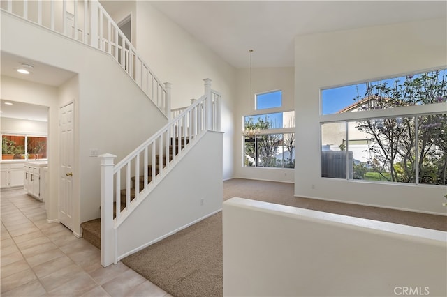 staircase with baseboards, tile patterned floors, a high ceiling, carpet floors, and recessed lighting