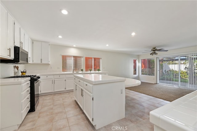 kitchen with range with gas stovetop, tile countertops, recessed lighting, light carpet, and a kitchen island