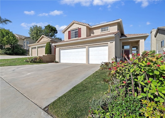 traditional-style house with driveway, a tile roof, a garage, and stucco siding