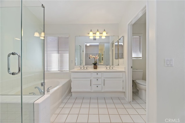 bathroom featuring double vanity, toilet, tile patterned floors, a garden tub, and a sink