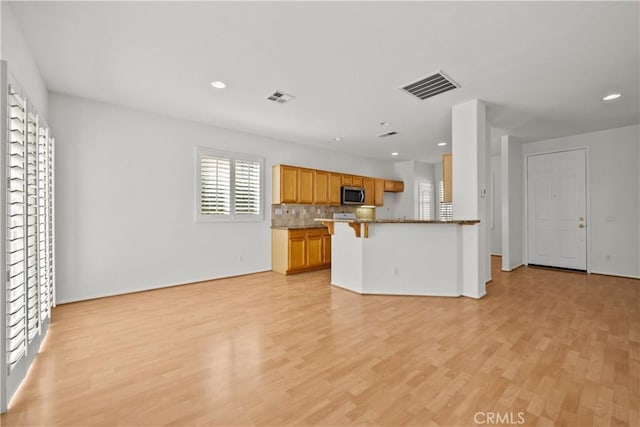 kitchen with open floor plan, stainless steel microwave, and visible vents