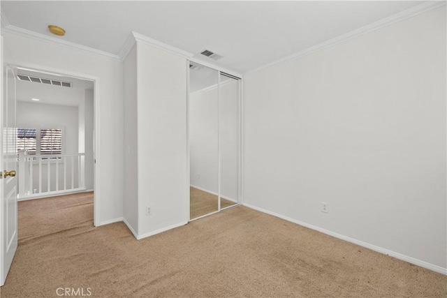 unfurnished bedroom with a closet, visible vents, ornamental molding, carpet flooring, and baseboards