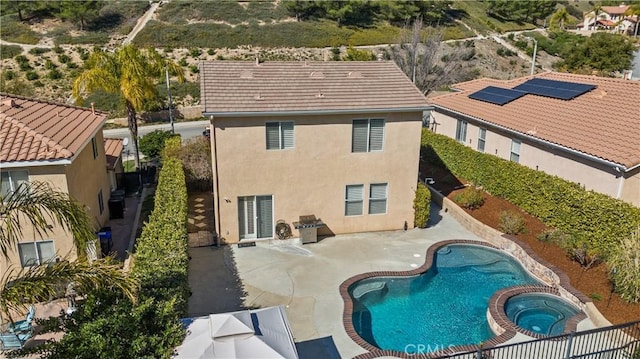 exterior space with a patio, stucco siding, a pool with connected hot tub, a fenced backyard, and a tiled roof