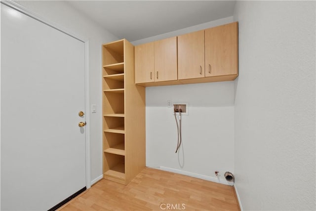 clothes washing area featuring cabinet space, light wood finished floors, baseboards, gas dryer hookup, and washer hookup