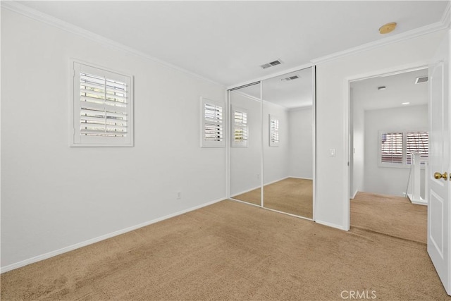 unfurnished bedroom with ornamental molding, multiple windows, carpet, and visible vents