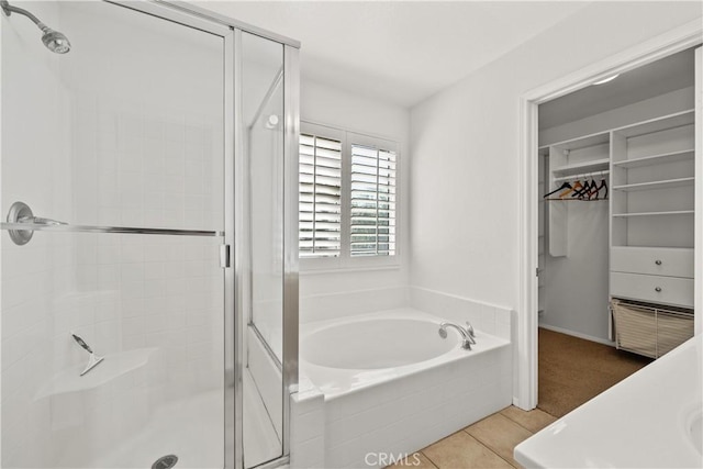 bathroom featuring a shower stall, a spacious closet, a bath, and tile patterned floors