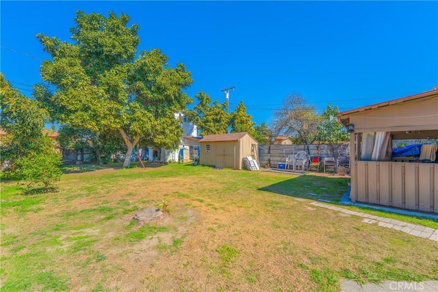 view of yard with an outbuilding, a storage unit, and fence