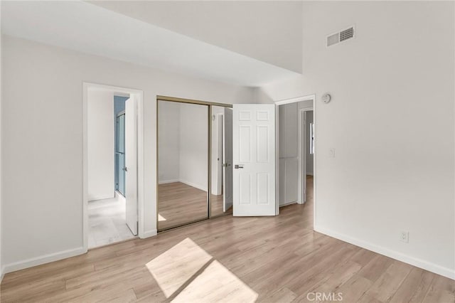 unfurnished bedroom with baseboards, visible vents, ensuite bath, light wood-type flooring, and a closet