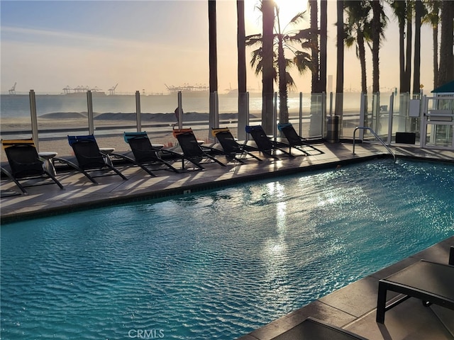 pool at dusk with a community pool and a patio