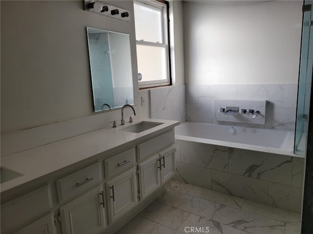 full bathroom with marble finish floor, a garden tub, and vanity