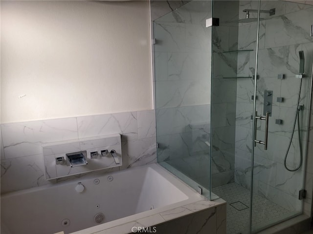 full bathroom featuring a marble finish shower and a tub with jets