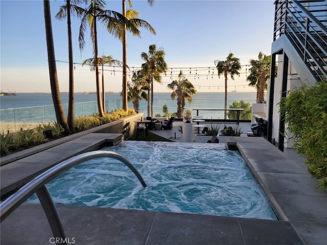 view of swimming pool with a water view and an in ground hot tub