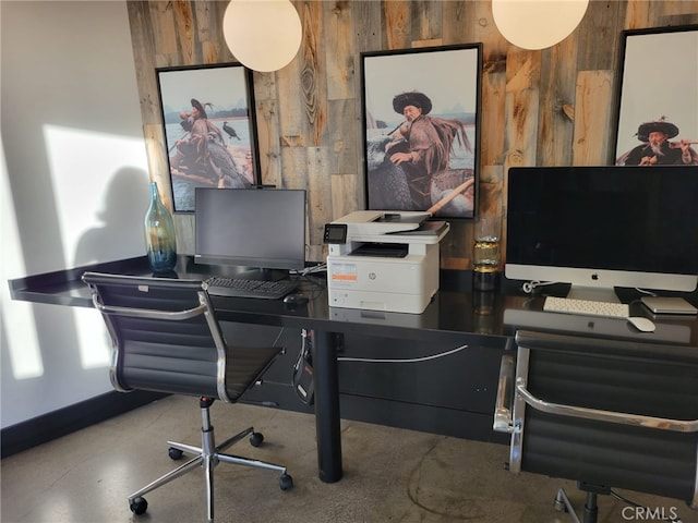 office featuring wood walls, finished concrete flooring, and baseboards