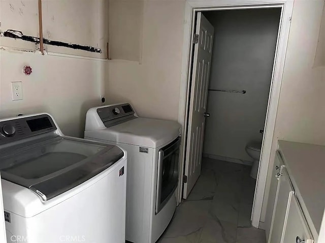 washroom featuring marble finish floor, separate washer and dryer, and cabinet space