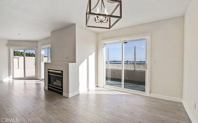 25 15th Pl Unit 101, Long Beach, CA 90802 - unfurnished living room with wood finished floors, baseboards, a chandelier, and a glass covered fireplace