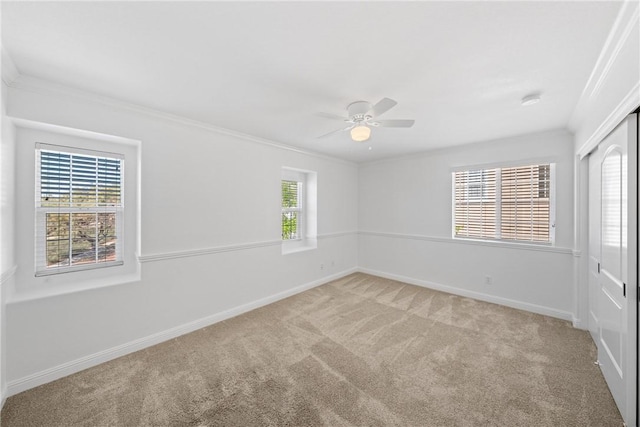 empty room featuring crown molding, baseboards, ceiling fan, and carpet flooring