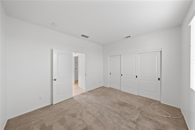 unfurnished bedroom with a closet, carpet flooring, and visible vents