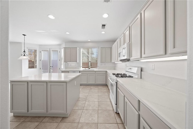 kitchen featuring light countertops, white appliances, visible vents, and a sink