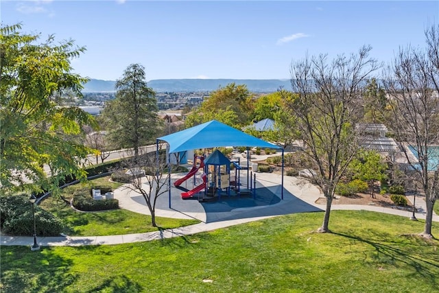 communal playground featuring a mountain view and a yard