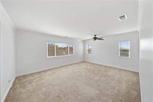 spare room featuring a healthy amount of sunlight, baseboards, visible vents, and light colored carpet