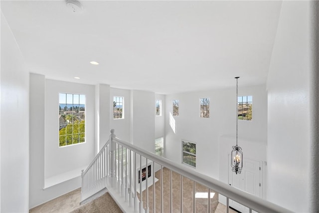 hall featuring carpet floors, recessed lighting, an upstairs landing, and an inviting chandelier