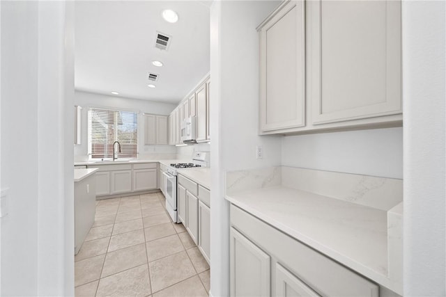 kitchen with white appliances, visible vents, light countertops, and a sink