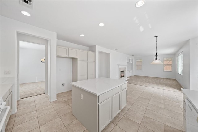 kitchen with light tile patterned floors, visible vents, a glass covered fireplace, a kitchen island, and recessed lighting