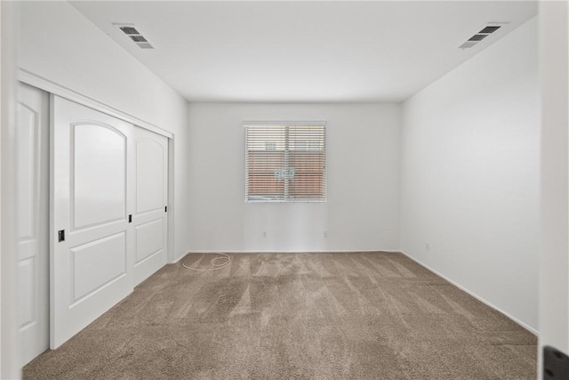 unfurnished bedroom featuring carpet, visible vents, and a closet