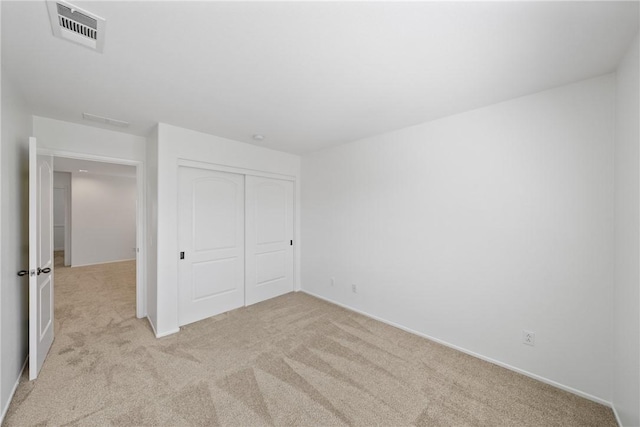 unfurnished bedroom featuring a closet, visible vents, and light carpet