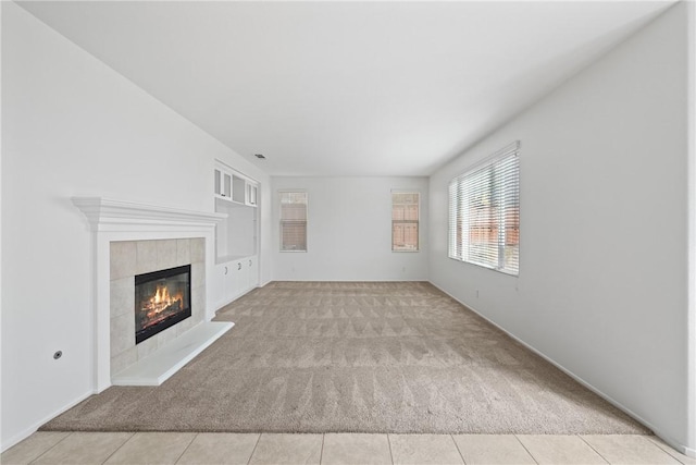 unfurnished living room featuring a tiled fireplace, carpet flooring, and tile patterned floors