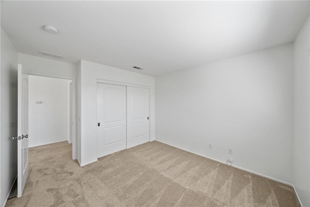 unfurnished bedroom with carpet floors, visible vents, and a closet