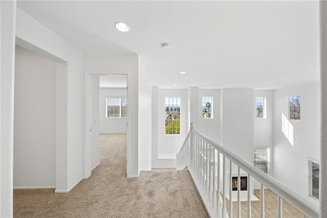 hallway with visible vents, baseboards, carpet, an upstairs landing, and recessed lighting