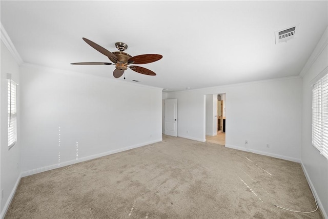 carpeted spare room featuring baseboards, a ceiling fan, visible vents, and crown molding