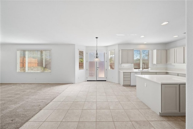 kitchen featuring light colored carpet, white dishwasher, light countertops, pendant lighting, and a sink