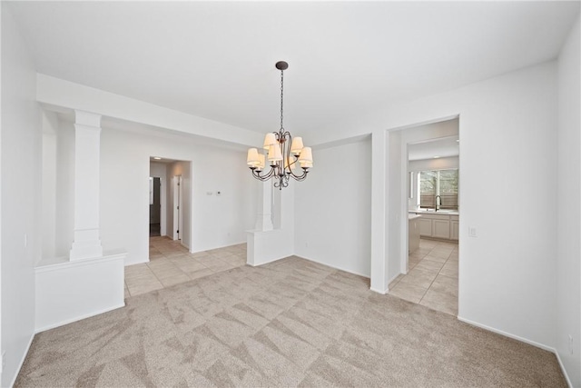 empty room featuring light tile patterned floors, light carpet, a sink, decorative columns, and an inviting chandelier