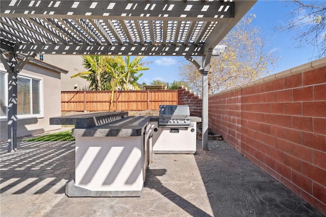 view of patio with exterior kitchen, a fenced backyard, area for grilling, and a pergola