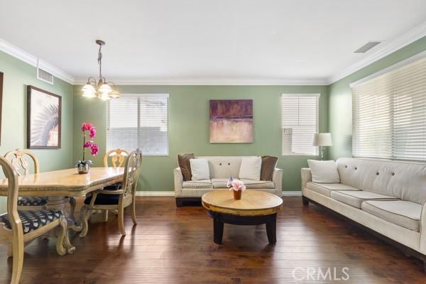 living area featuring ornamental molding, wood finished floors, visible vents, and an inviting chandelier