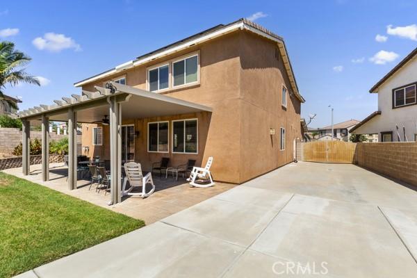 back of property featuring a yard, stucco siding, a gate, a patio area, and fence