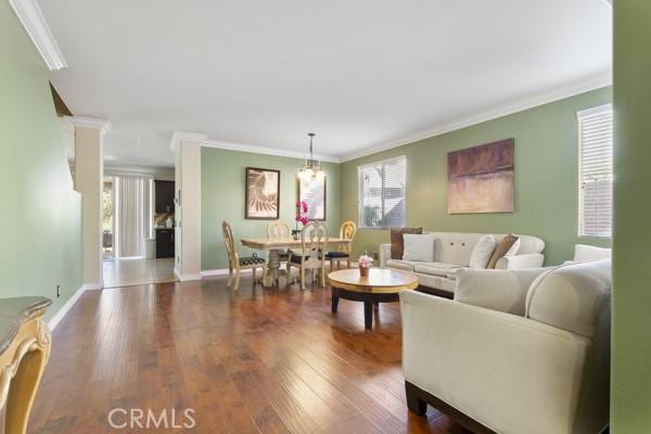 living area featuring crown molding, baseboards, and wood finished floors