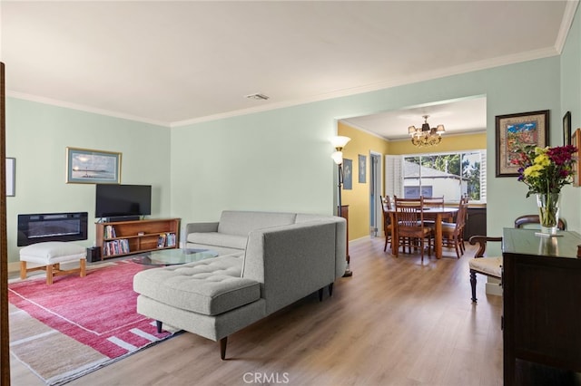 living room featuring crown molding, an inviting chandelier, wood finished floors, and visible vents