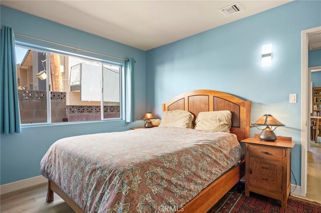 bedroom with wood finished floors, visible vents, and multiple windows