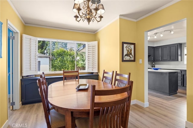 dining area featuring crown molding, an inviting chandelier, light wood-style flooring, and baseboards