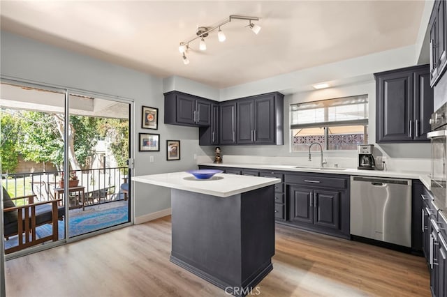kitchen featuring a sink, light wood-style flooring, a kitchen island, light countertops, and stainless steel dishwasher