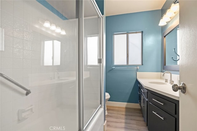 full bathroom featuring toilet, a shower with shower door, wood finished floors, and vanity