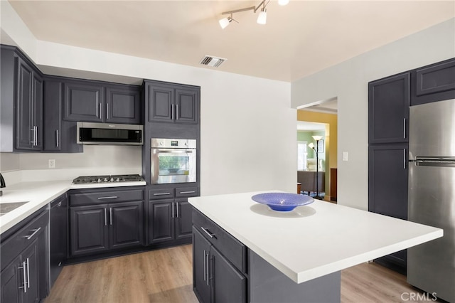 kitchen featuring visible vents, stainless steel appliances, a kitchen island, light countertops, and light wood-type flooring