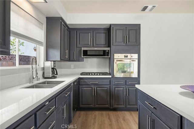 kitchen with a sink, appliances with stainless steel finishes, visible vents, light countertops, and light wood finished floors