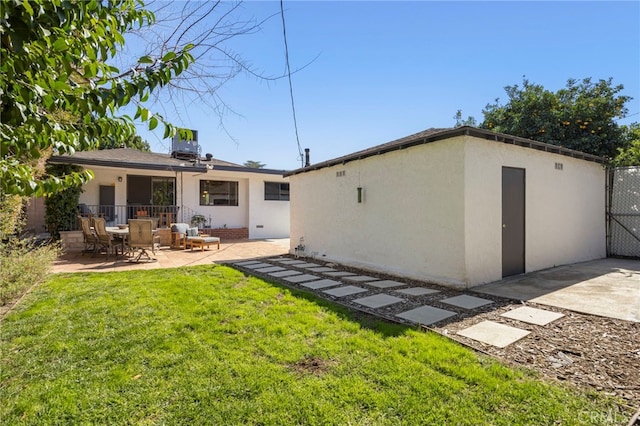 back of house featuring a patio, a gate, a lawn, stucco siding, and fence