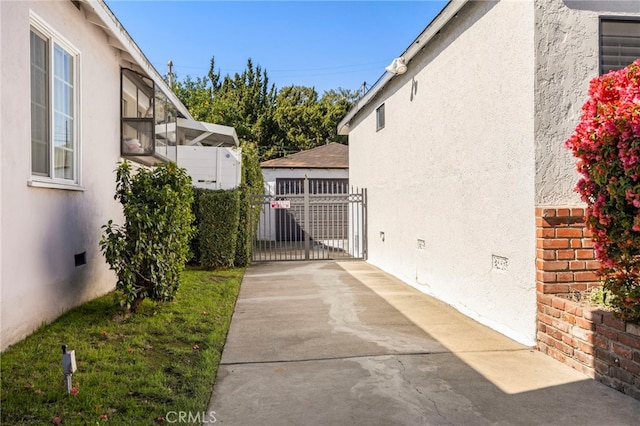 view of side of property with a gate, stucco siding, and crawl space