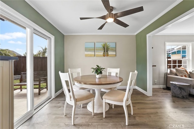 dining space with baseboards, crown molding, light wood finished floors, and ceiling fan